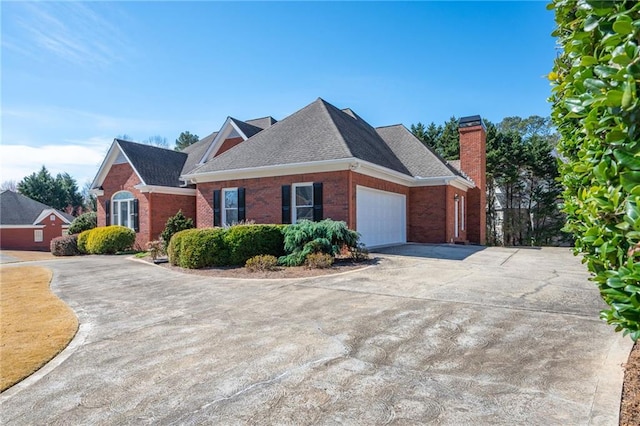 view of front facade featuring an attached garage, brick siding, concrete driveway, roof with shingles, and a chimney