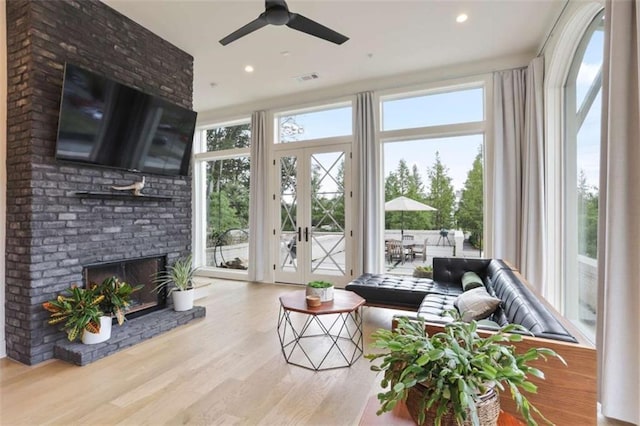 interior space featuring a fireplace, a wealth of natural light, light hardwood / wood-style floors, and ceiling fan