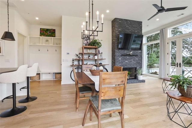 dining area with ceiling fan, a brick fireplace, light hardwood / wood-style floors, and french doors