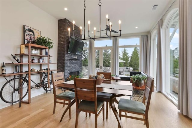 dining space featuring a fireplace, light hardwood / wood-style flooring, and french doors