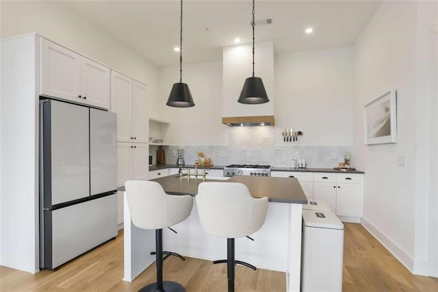 kitchen featuring white cabinetry, light hardwood / wood-style flooring, fridge, pendant lighting, and backsplash