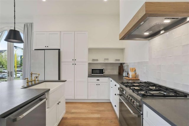 kitchen featuring light hardwood / wood-style flooring, stainless steel appliances, white cabinets, decorative light fixtures, and custom exhaust hood