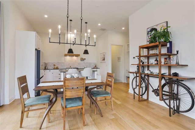 dining area featuring light hardwood / wood-style flooring, a chandelier, and a high ceiling