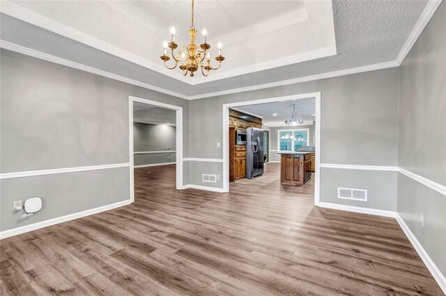 unfurnished dining area featuring a notable chandelier, a raised ceiling, and hardwood / wood-style floors