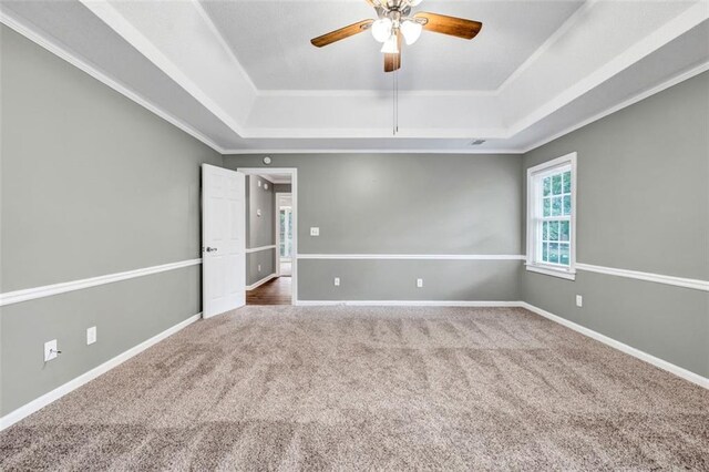 unfurnished bedroom featuring ornamental molding, ceiling fan, carpet, and a raised ceiling