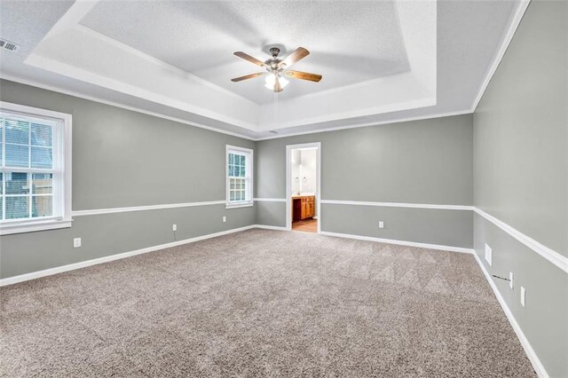 empty room featuring a tray ceiling, carpet flooring, and ceiling fan