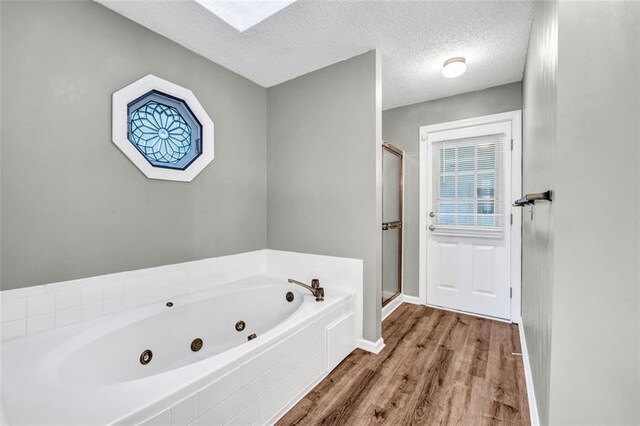 bathroom featuring a skylight, hardwood / wood-style flooring, independent shower and bath, and a textured ceiling