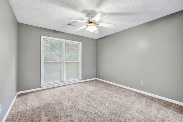 carpeted spare room featuring ceiling fan and a textured ceiling