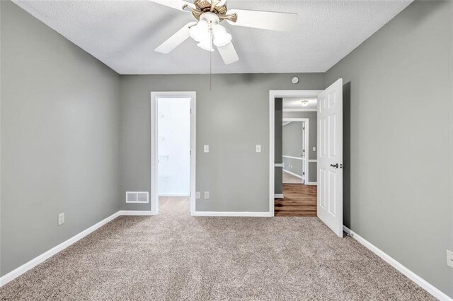 unfurnished bedroom featuring light carpet, ceiling fan, and a textured ceiling