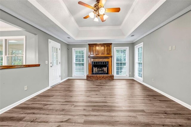 unfurnished living room featuring ceiling fan, hardwood / wood-style flooring, a fireplace, and plenty of natural light