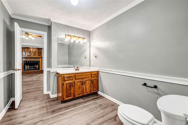 bathroom featuring ceiling fan, toilet, hardwood / wood-style flooring, vanity, and a textured ceiling