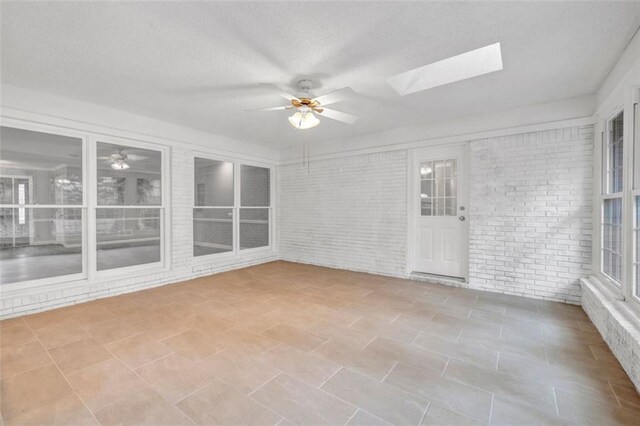 unfurnished sunroom with a skylight and ceiling fan