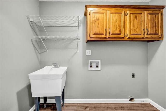 laundry area featuring wood-type flooring, hookup for an electric dryer, hookup for a washing machine, and cabinets