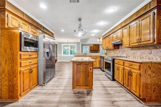 kitchen featuring appliances with stainless steel finishes, a kitchen island, decorative light fixtures, and light hardwood / wood-style flooring