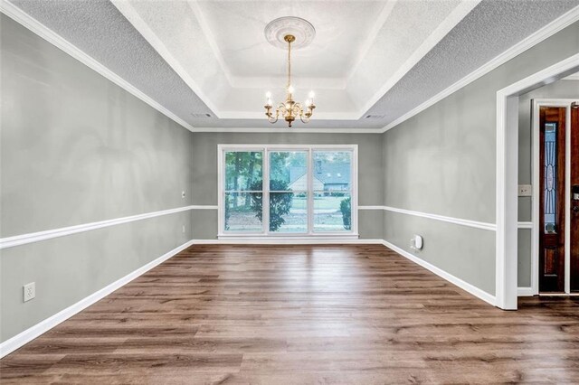 empty room featuring an inviting chandelier, ornamental molding, and hardwood / wood-style flooring