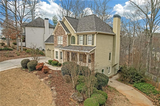 view of front of home featuring driveway, a shingled roof, and a chimney