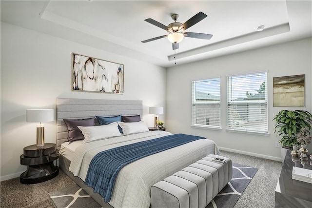 carpeted bedroom with ceiling fan and a raised ceiling