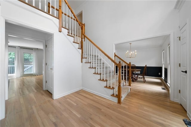 stairway with wood-type flooring and an inviting chandelier