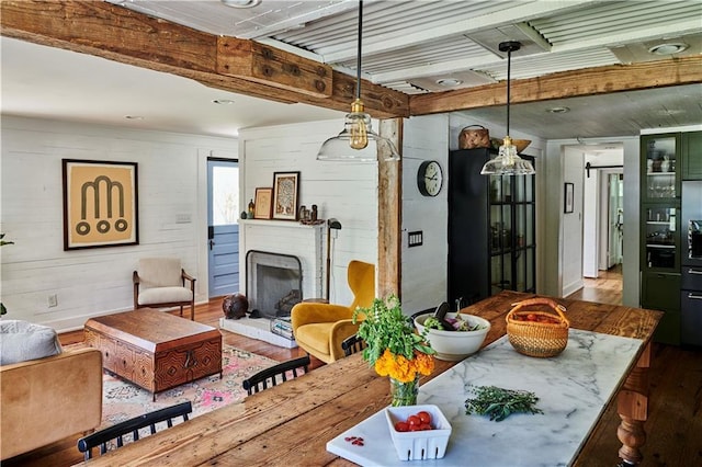 interior space featuring hardwood / wood-style flooring, beam ceiling, and a brick fireplace