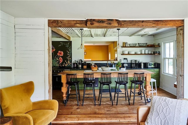 bar with hardwood / wood-style flooring, butcher block counters, hanging light fixtures, and beamed ceiling