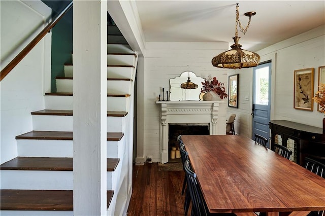 dining space with dark wood-type flooring and wood walls