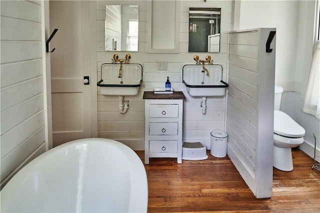 bathroom featuring toilet, sink, a bath, and hardwood / wood-style floors