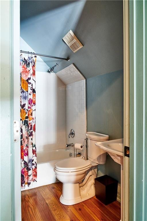 bathroom with hardwood / wood-style flooring, lofted ceiling, toilet, and shower / tub combo