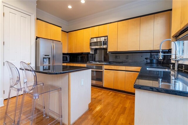 kitchen featuring sink, crown molding, a center island, light wood-type flooring, and stainless steel appliances