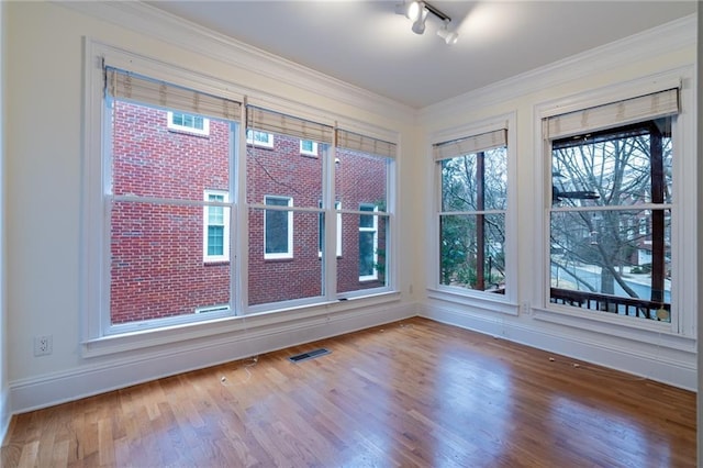 spare room featuring wood-type flooring, track lighting, and crown molding