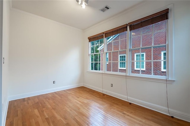 spare room featuring crown molding and light hardwood / wood-style flooring