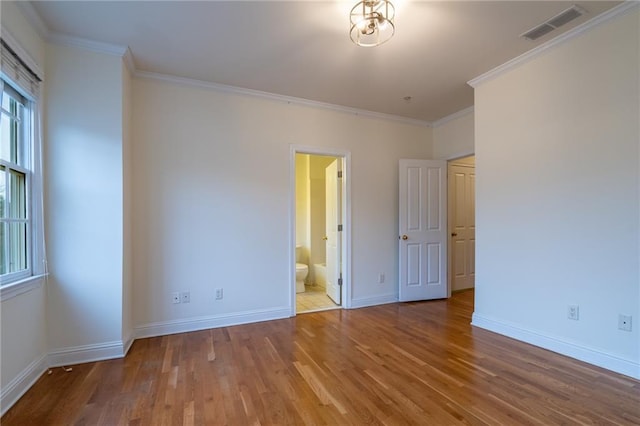 unfurnished bedroom with crown molding, wood-type flooring, and ensuite bath