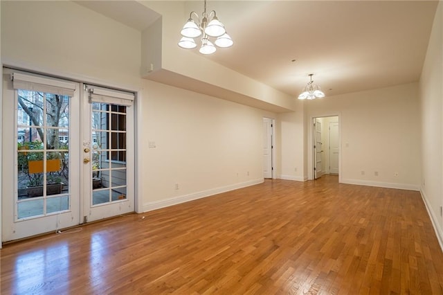 unfurnished room with wood-type flooring, an inviting chandelier, and french doors