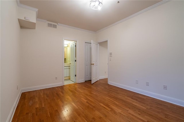 unfurnished bedroom featuring hardwood / wood-style floors, ornamental molding, and ensuite bathroom