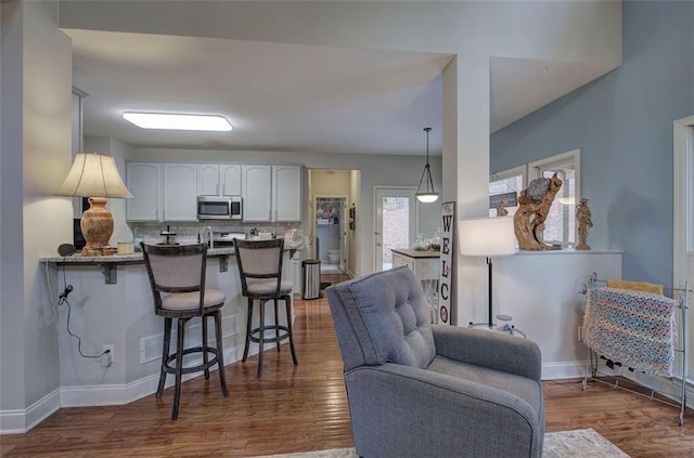 kitchen featuring a breakfast bar, dark hardwood / wood-style flooring, kitchen peninsula, and white cabinets