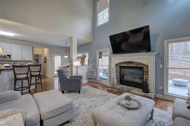 living room featuring a fireplace, dark wood-type flooring, and a high ceiling