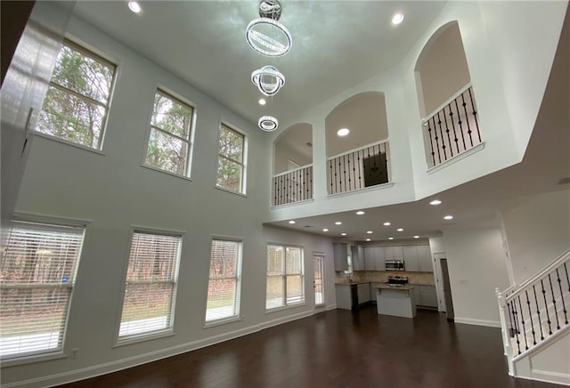 unfurnished living room with a high ceiling, stairway, recessed lighting, and baseboards