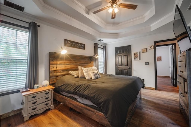 bedroom featuring ceiling fan, a raised ceiling, and wood-type flooring