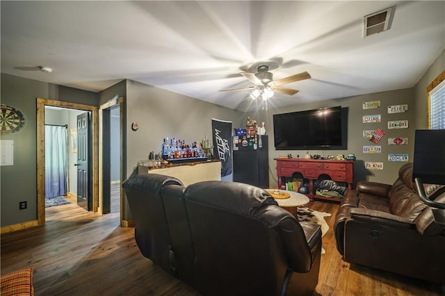 living room featuring ceiling fan, indoor bar, and wood-type flooring