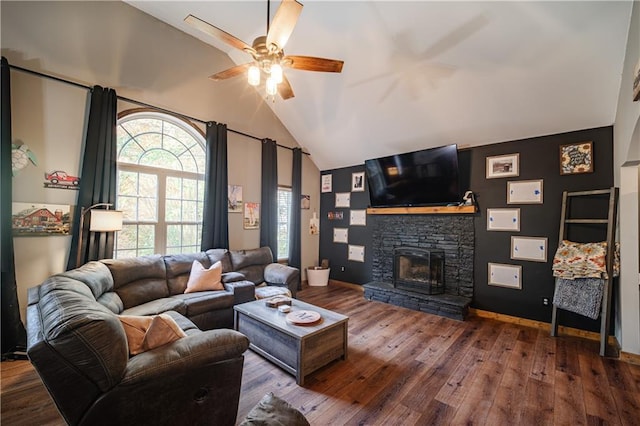 living room with lofted ceiling, ceiling fan, wood-type flooring, and a stone fireplace