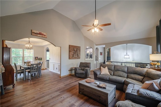 living room with lofted ceiling, ceiling fan with notable chandelier, and wood-type flooring