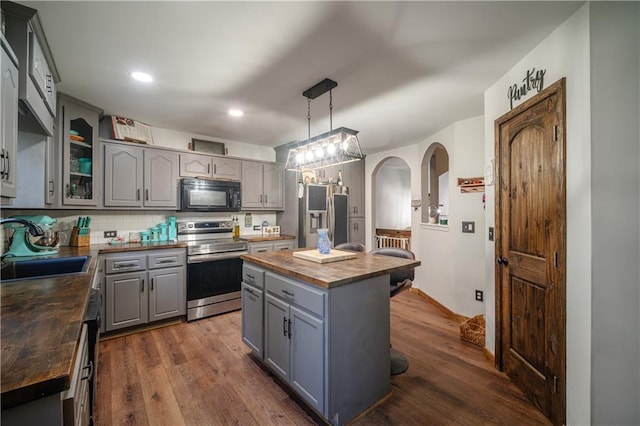 kitchen with a center island, stainless steel electric range oven, butcher block countertops, decorative backsplash, and decorative light fixtures