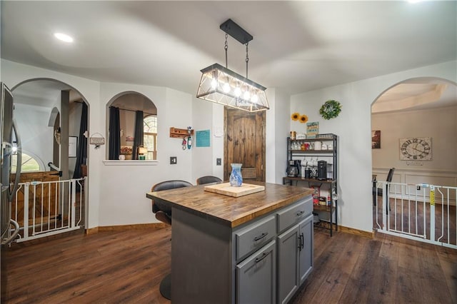 kitchen with butcher block counters, decorative light fixtures, a kitchen island, dark hardwood / wood-style flooring, and gray cabinetry