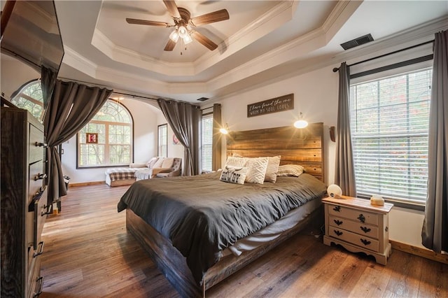 bedroom with ceiling fan, a tray ceiling, crown molding, and hardwood / wood-style floors