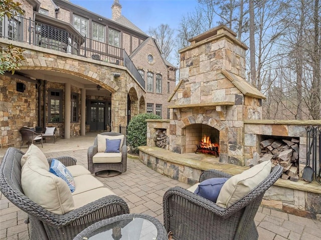 view of terrace with an outdoor living space with a fireplace and a balcony