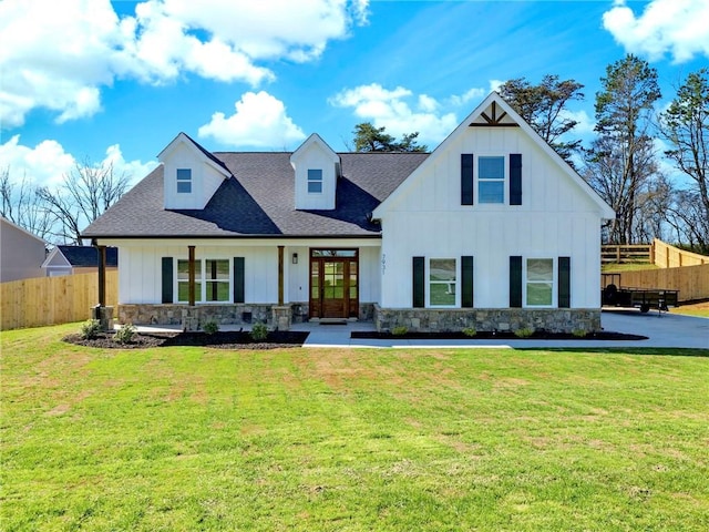 modern farmhouse style home with board and batten siding, stone siding, fence, and a front lawn