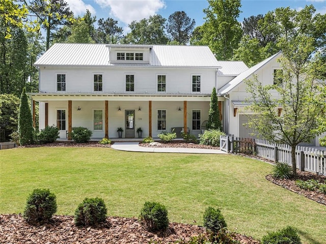modern inspired farmhouse featuring a garage, a front lawn, fence, covered porch, and metal roof