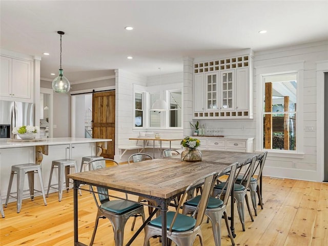 dining room with recessed lighting, a barn door, and light wood-type flooring