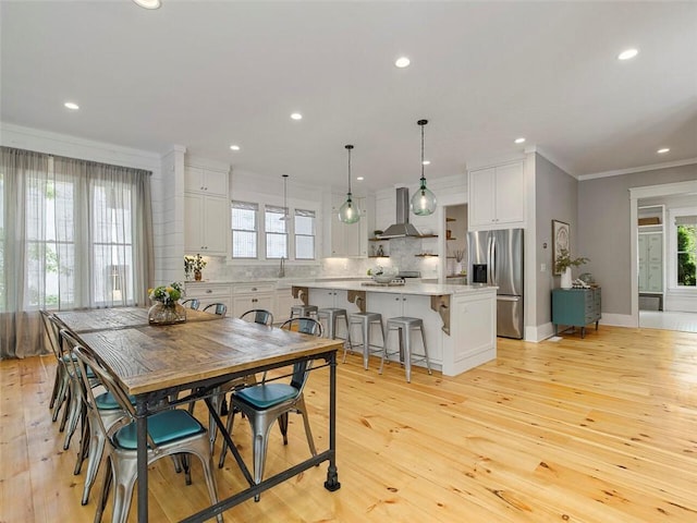 dining room featuring crown molding, light wood-style floors, and a healthy amount of sunlight
