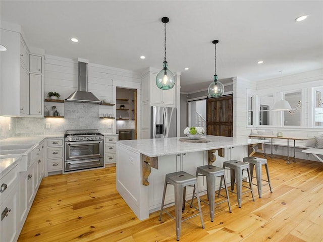 kitchen featuring decorative backsplash, a kitchen island, appliances with stainless steel finishes, open shelves, and wall chimney exhaust hood