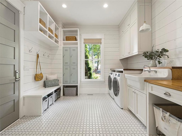 washroom featuring washing machine and clothes dryer, wood walls, cabinet space, a sink, and recessed lighting